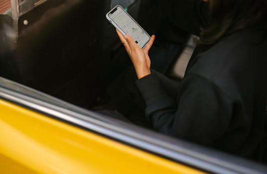 A woman using a smartphone for navigation in a yellow taxi. Perfect for travel and technology themes.