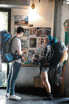 Two backpackers examining maps and brochures inside a travel information center.