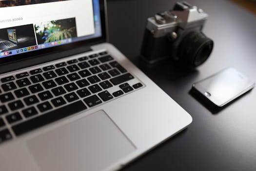 Lifestyle workspace setup with a laptop, camera, and smartphone on a desk.