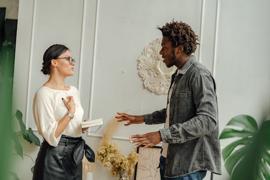 Two adults engaging in a friendly conversation indoors, sharing ideas.