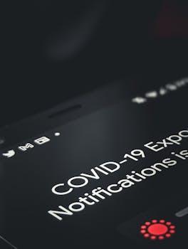 Close-up of smartphone screen showing COVID-19 exposure notification with dark background.