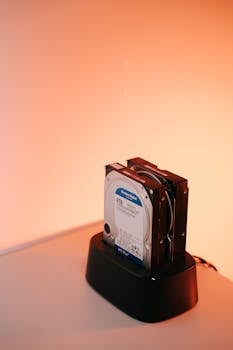 Dual external hard drives on a docking station with an orange backdrop.