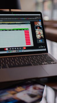Laptop displaying a remote video meeting in a modern office setting.