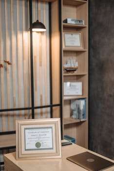 Stylish office interior featuring a framed diploma, modern desk, and elegant lighting.