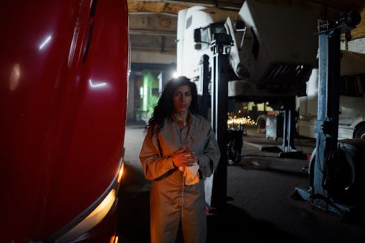 Woman mechanic standing confidently in a garage surrounded by trucks, symbolizing empowerment.
