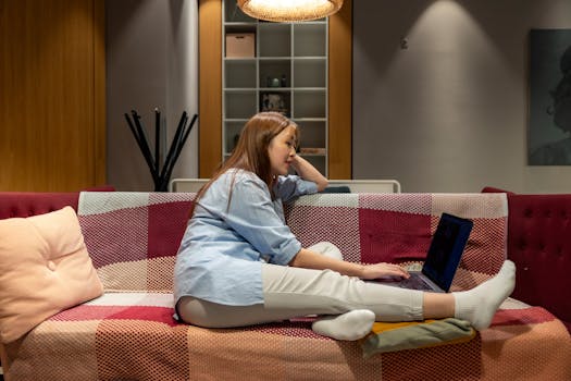 Woman working on a laptop in a cozy indoor environment, embodying the remote work lifestyle.