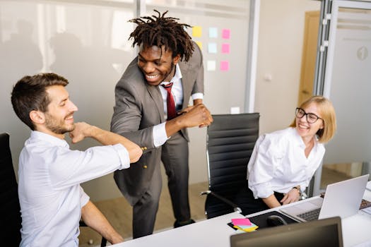 A diverse team of colleagues celebrating with a joyful elbow bump in a modern office setting.