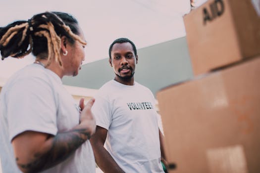 Two volunteers organizing aid packages and communicating during an outdoor charity event.